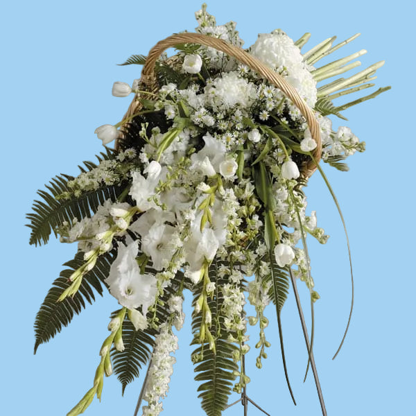 Floral arrangement in a basket with white flowers and greenery on a gray background