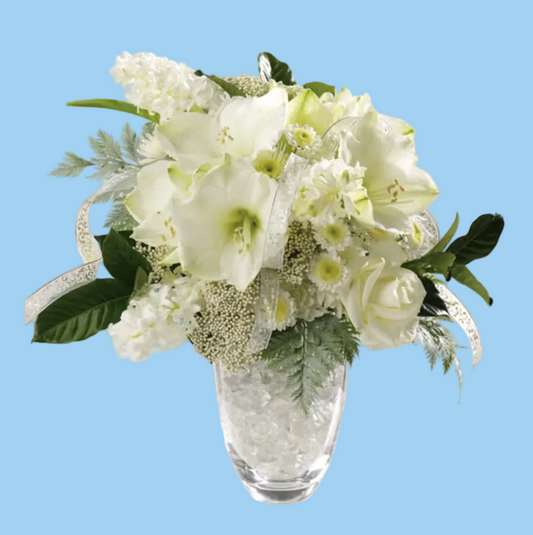 Bouquet of white flowers in a clear glass vase on a white surface.