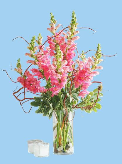 Bouquet of pink flowers in a clear vase on a white surface with a neutral background