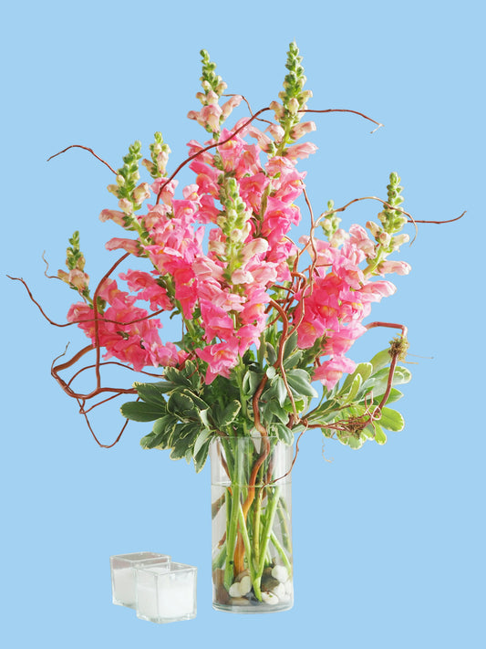 Bouquet of pink flowers in a clear vase on a white surface with a neutral background