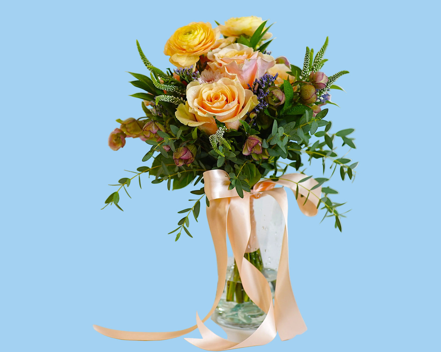 Bouquet of flowers with ribbons in a clear vase on a light background