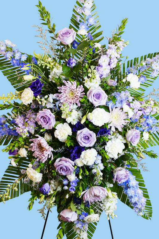 Elegant floral arrangement with purple, white, and blue flowers on a stand.