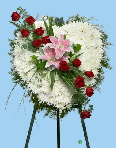 Floral arrangement with white flowers, red roses, and pink lilies on a stand.